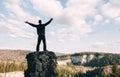 Young man standing with raised hands on top of a mountain and enjoying valley view Royalty Free Stock Photo