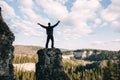 Young man standing with raised hands on top of a mountain and enjoying valley view Royalty Free Stock Photo