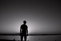 The young man is standing before the river bank with balck and white Sunrise or sunset