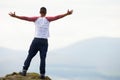 Young Man Standing On Rock With Outstretched Arms