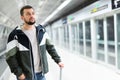 Young man standing with suitcase on subway station platform Royalty Free Stock Photo