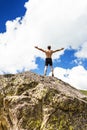 Young man standing on top of a cliff with arms raised Royalty Free Stock Photo