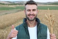 Young man standing in wheat field and showing thumb up while winking and smiling Royalty Free Stock Photo