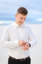 Young man standing in winter steppe and looking at watch. Royalty Free Stock Photo