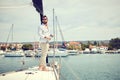 A young man standing on the yacht and enjoying the view on the town on the seaside. Summer, sea, vacation