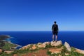 Young man stands on the edge of rock and watchs mediterranean sea in Akamas Peninsula National Park, Cyprus. Traveler enjoy view Royalty Free Stock Photo