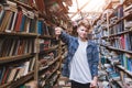 Young man stands in a public library and shows a finger down. Dislike library and books Royalty Free Stock Photo