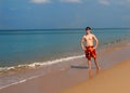 A young man stands on the sand on the shores of Andamand Bay in Phuket in shorts and sunbathes