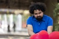 a man sitting on a bench holding flowers with red balloons Royalty Free Stock Photo