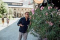 a young man stands on the street near a bush and happily sniffs Royalty Free Stock Photo