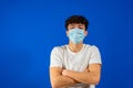 Young man in sterile face mask posing isolated on blue background studio portrait. Epidemic pandemic rapidly spreading Royalty Free Stock Photo