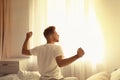 Young man stretching on bed at home. Lazy morning Royalty Free Stock Photo