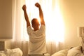 Young man stretching on bed at home. Lazy morning