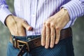 Young Man Puts on a Belt in Trousers Close Up