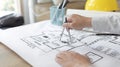 Young man structural design or engineer is using a measuring circle around a floor plan or blueprint