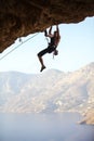 Young man struggling to climb ledge on cliff