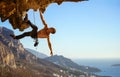 Young man struggling to climb ledge on cliff