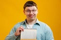 Young man student in glasses holds stack of university books from college library on yellow background. Happy guy smiles, he is Royalty Free Stock Photo