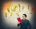 Young man, student or teacher, looking with interest at a red book in his hand, reading the textbook title. Education concept,