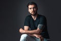 Young man in studio on dark background. Handsome brunette with beard and tattoo in black t-shirt. Portrait Royalty Free Stock Photo