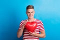 A young man in a studio, holding red heart balloon in front of him. Royalty Free Stock Photo