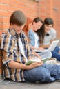 Young man studying book friends in background Royalty Free Stock Photo