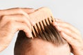Young man styling his hair with a wooden comb. Hair styling at home. Advertising concept of shampoo for healthy hair and Royalty Free Stock Photo
