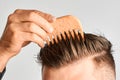 Young man styling his hair with a wooden comb. Hair styling at home. Advertising concept of shampoo for healthy hair and Royalty Free Stock Photo