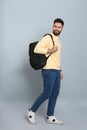 Young man with stylish backpack walking on light grey background Royalty Free Stock Photo