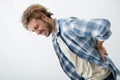 Young man suffering from back pain on light background