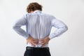 Young man suffering from back pain on light background