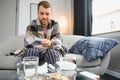 Young man suffering from cold at his home. Shot of a young man sitting on his bed while feeling unwell at home. Trying Royalty Free Stock Photo