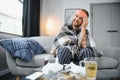 Young man suffering from cold at his home. Shot of a young man sitting on his bed while feeling unwell at home. Trying Royalty Free Stock Photo