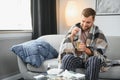 Young man suffering from cold at his home. Shot of a young man sitting on his bed while feeling unwell at home. Trying Royalty Free Stock Photo