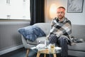 Young man suffering from cold at his home. Shot of a young man sitting on his bed while feeling unwell at home. Trying Royalty Free Stock Photo