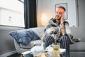 Young man suffering from cold at his home. Shot of a young man sitting on his bed while feeling unwell at home. Trying Royalty Free Stock Photo