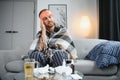 Young man suffering from cold at his home. Shot of a young man sitting on his bed while feeling unwell at home. Trying Royalty Free Stock Photo