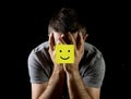 Young man suffering depression and stress alone with smiley face post it note