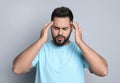 Young man suffering from headache on light grey background