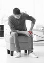 Young man suffering from knee pain at home, Royalty Free Stock Photo