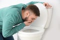 Young man suffering from nausea over toilet bowl Royalty Free Stock Photo