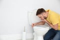 Young man suffering from nausea over toilet bowl Royalty Free Stock Photo