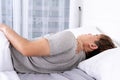 Young man suffering neck and shoulder pain from uncomfortable bed. Healthcare medical or daily life concept Royalty Free Stock Photo