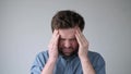 Young man suffering from severe headache, pressing fingers to temples, closing eyes to relieve pain. Royalty Free Stock Photo