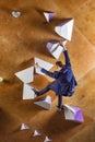 Young man in suit climbing difficult route on artificial wall in bouldering gym. Career challenges concept