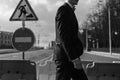 Young man in a suit is walking along a pedestrian crossing. On the road sign is under construction. Royalty Free Stock Photo