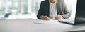 Young man in suit writing business papers at desk in modern coworking office