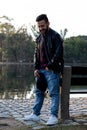 happy Latin man in a leather jacket and blue jean pants standing by a lake Royalty Free Stock Photo