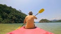 Man with sunglasses and hat rows pink plastic canoe along sea ag Royalty Free Stock Photo