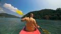 Man with sunglasses and hat rows pink plastic canoe along sea ag Royalty Free Stock Photo